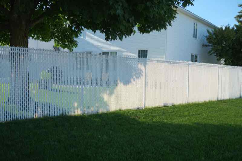 White vinyl privacy fence beside a green lawn